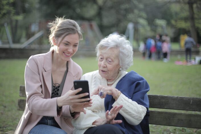 Mujer sosteniendo un teléfono a una mujer mayor