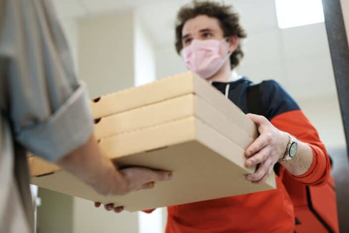 Chico entregando tres cajas de pizza a un cliente