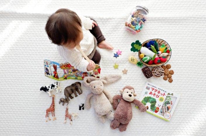 niño sentado mientras la tela rodeada de juguetes