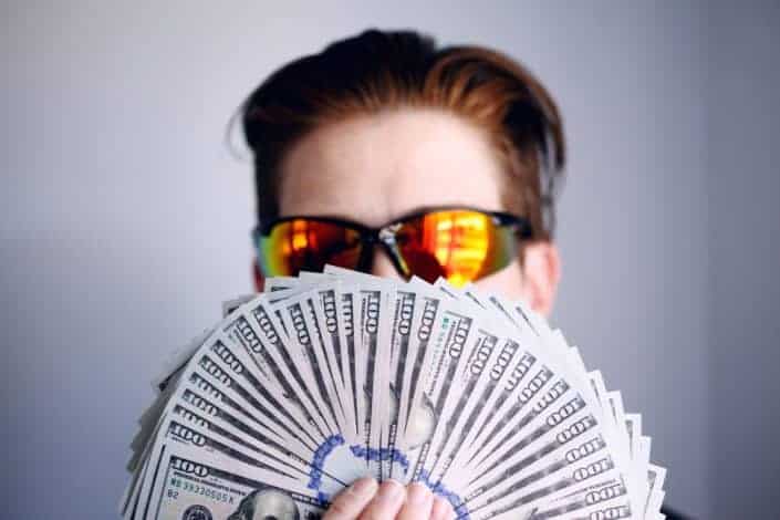 hombre con ventilador de billetes de cien dólares.