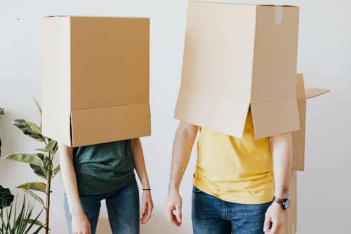  Pareja irreconocible llevando cajas de cartón en la cabeza.
