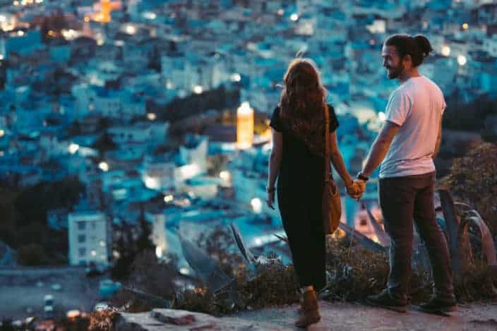 pareja tomados de la mano mientras ve la ciudad