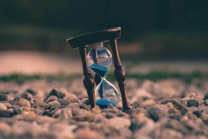Fotografía de enfoque selectivo de reloj de arena azul sobre piedras