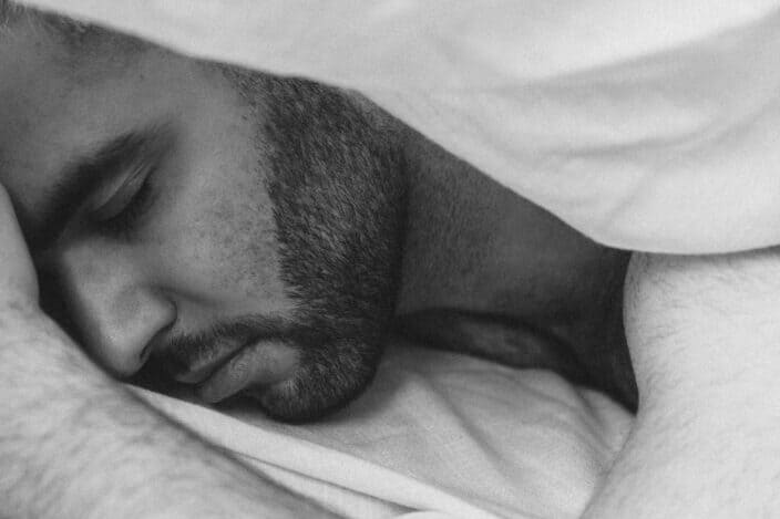 hombre barbudo durmiendo pacíficamente bajo las sábanas