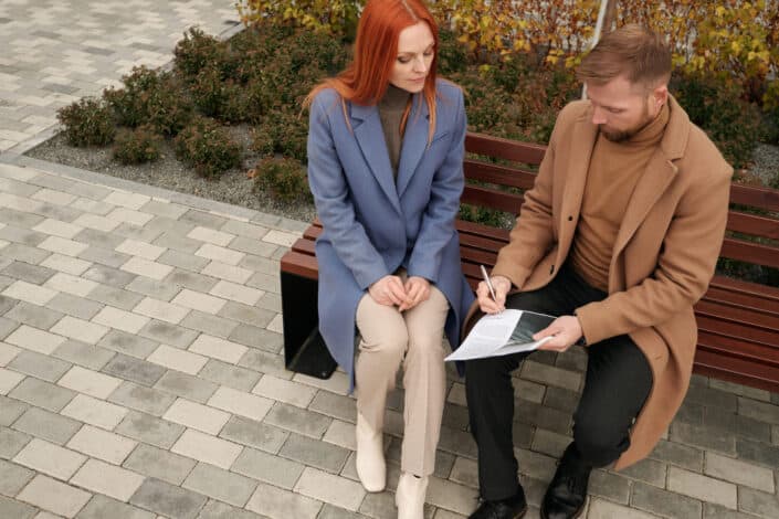 hombre y mujer sentados en un banco discutiendo sobre algo