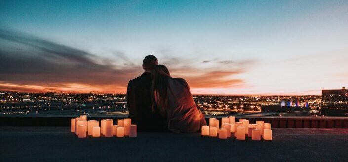  pareja sentada en el campo frente a la ciudad