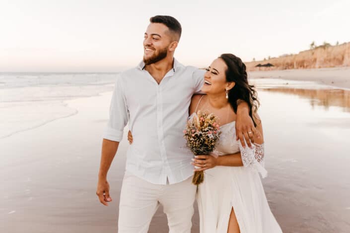 Encantado de pareja de recién casados ​​caminando en la playa