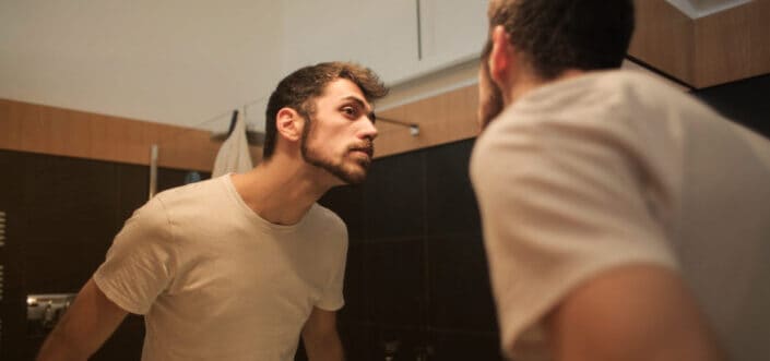 A boy looking at himself in the mirror.