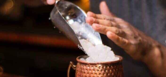 A guy putting ice cubes in a cup.