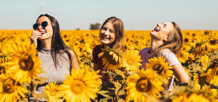 Amigas divirtiéndose en un jardín de girasoles en un día soleado