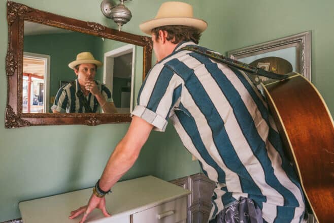 Man with a guitar, checking himself in the mirror. - how to remove a hickey