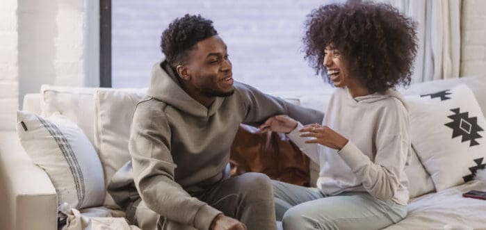 pareja sentada en un sofá teniendo una conversación divertida