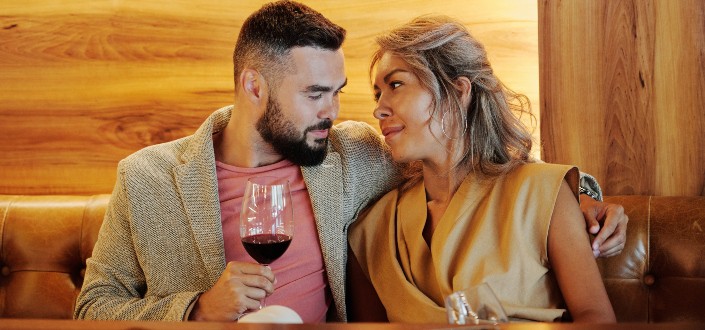 Pareja romántica sentada en un sofá mientras bebe vino