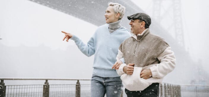 Una mujer más alta caminando del brazo con un hombre más bajo en una nieve frÃa