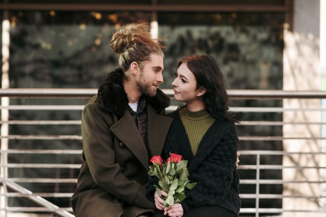 pareja sosteniendo rosas rojas mirándose el uno al otro - 21 preguntas para una nueva relación